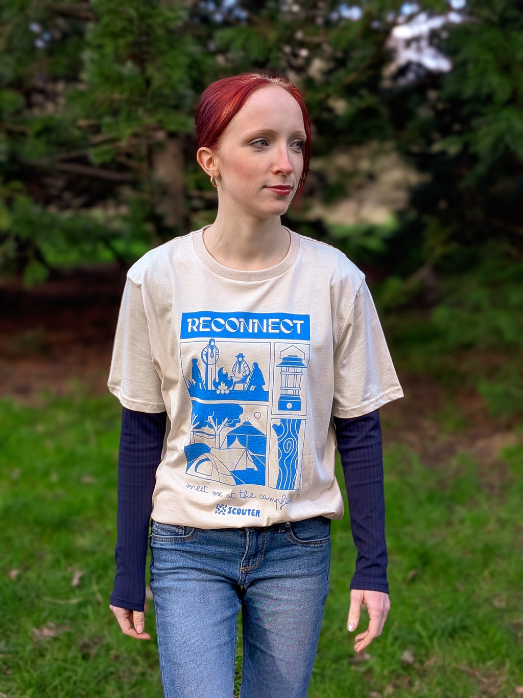 Person wearing a beige t-shirt with a graphic design outdoors